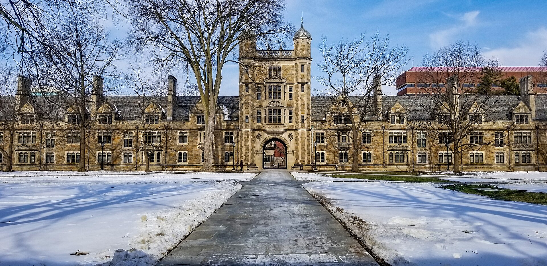 Snow-covered lawns and the Gothic stone Law Quadrangle of the University of Michigan in Ann Arbor on a sunny winter day.