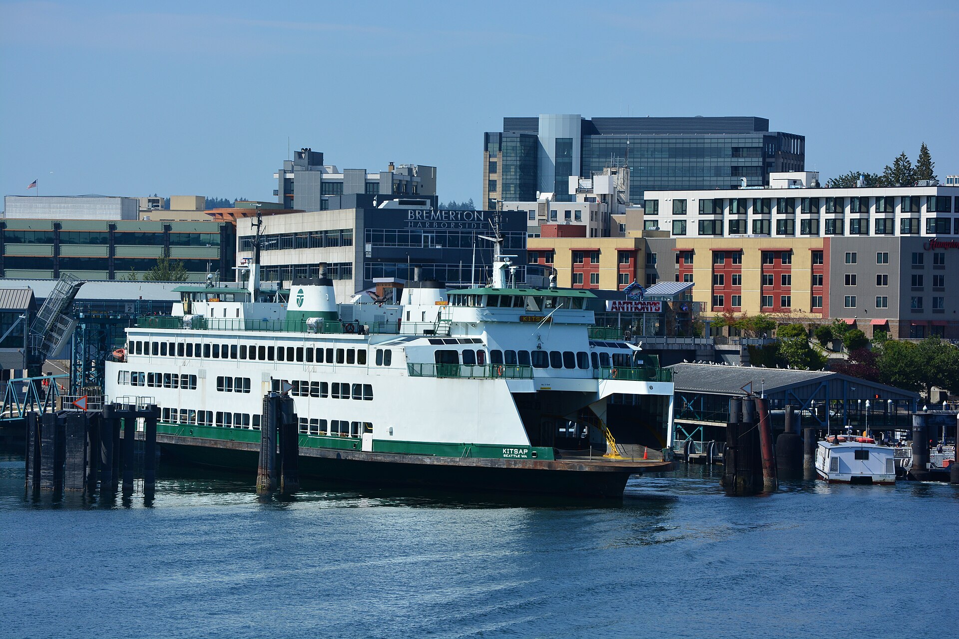 A green-and-white Washington State ferry docked at the Bremerton terminal in front of the downtown waterfront buildings.