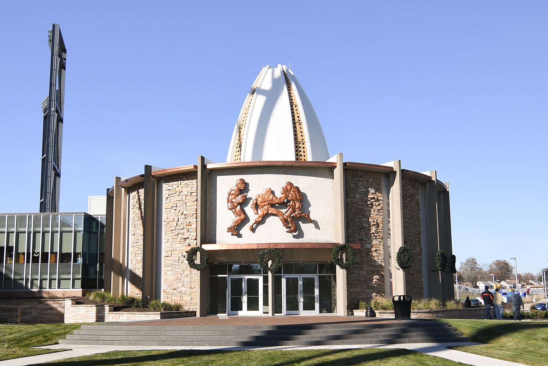 The Pro Football Hall of Fame's white football-shaped dome and stone rotunda in Canton under a clear blue sky.