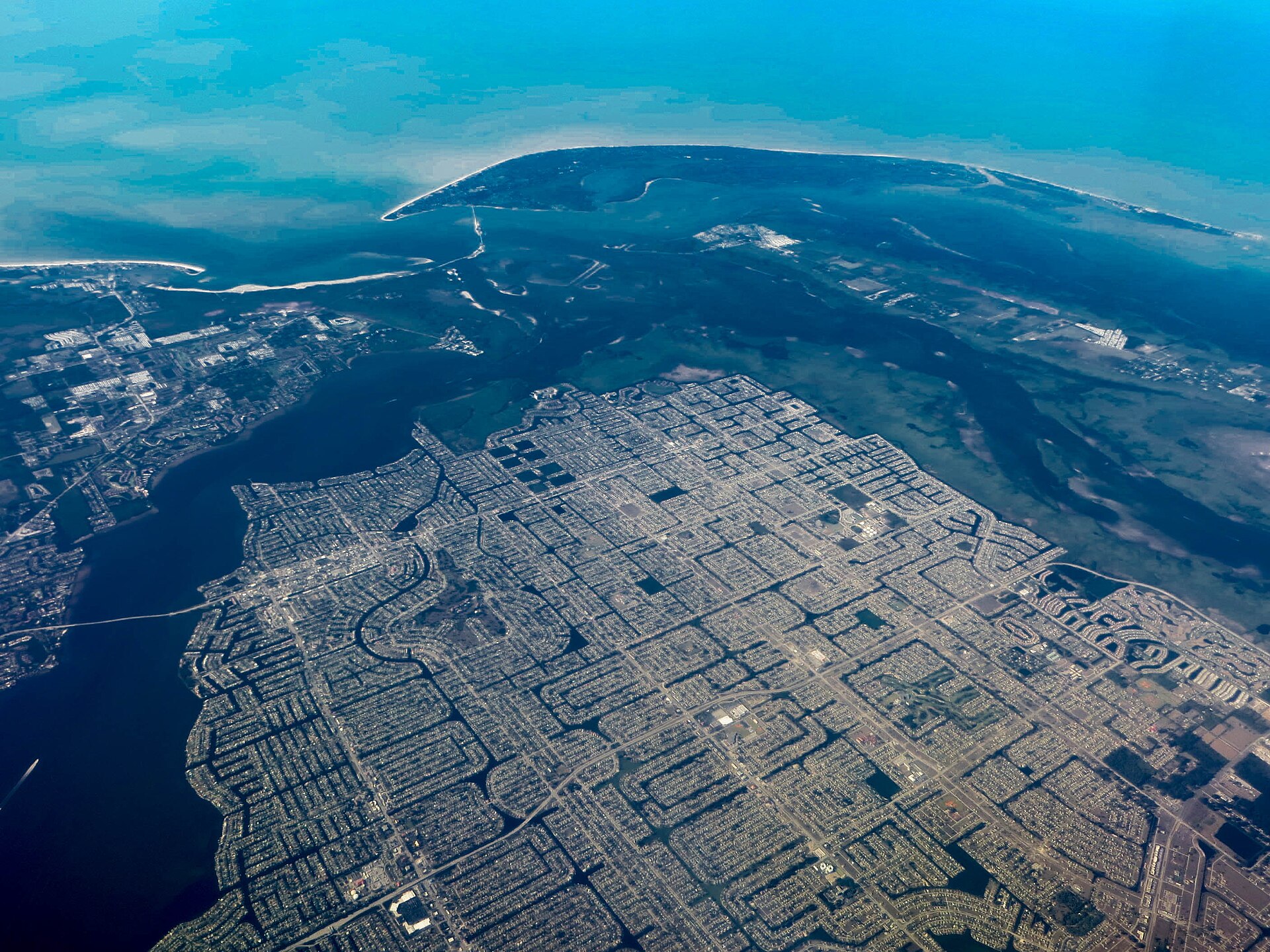Cape Coral's grid of canals and streets seen from the air, with open water and the Gulf coast beyond.