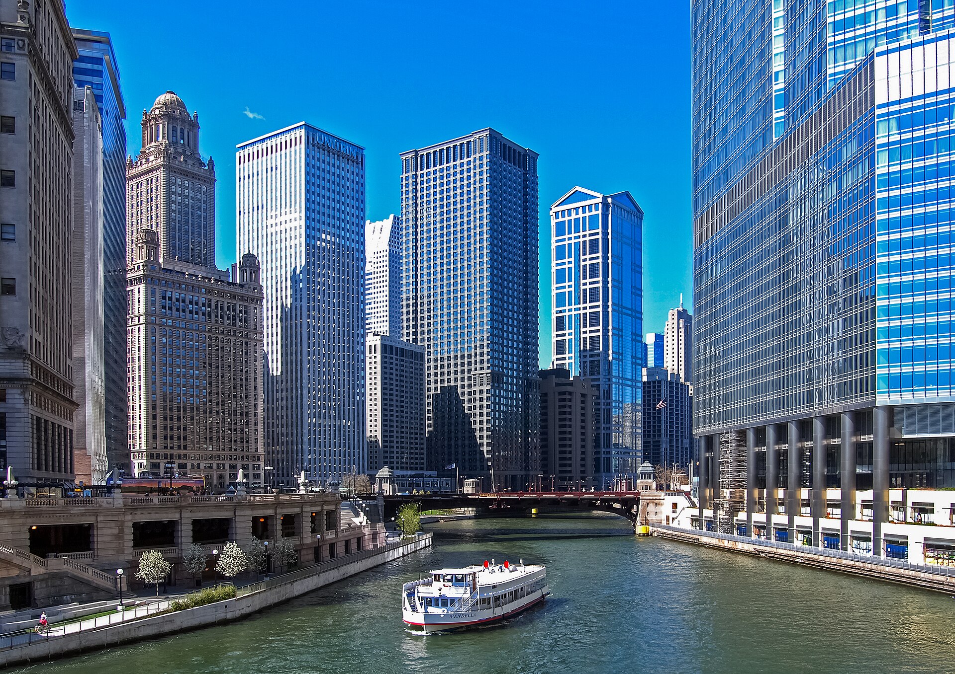 A tour boat on the Chicago River between the downtown towers on a sunny day.
