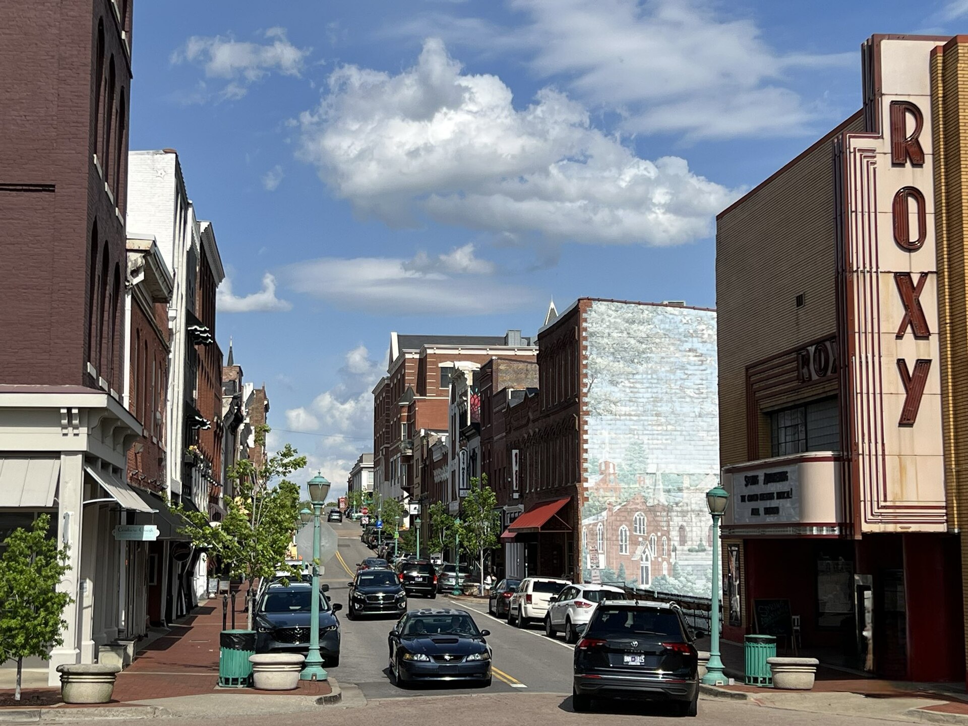 Historic brick buildings and the vertical Roxy theatre sign along Franklin Street in downtown Clarksville under a blue sky.