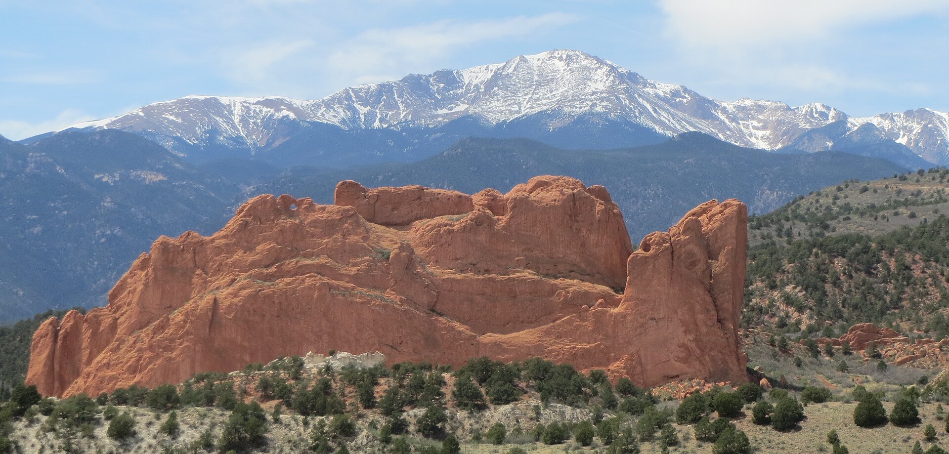 Red sandstone rocks of the Garden of the Gods in Colorado Springs, with snow-capped Pikes Peak rising behind.