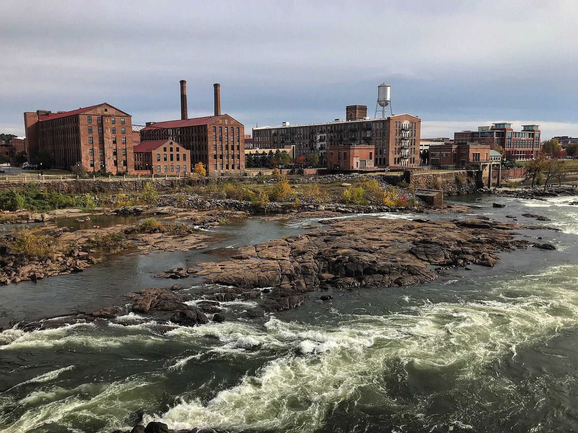 Whitewater rapids on the Chattahoochee River below the old brick mill buildings of downtown Columbus's riverfront.