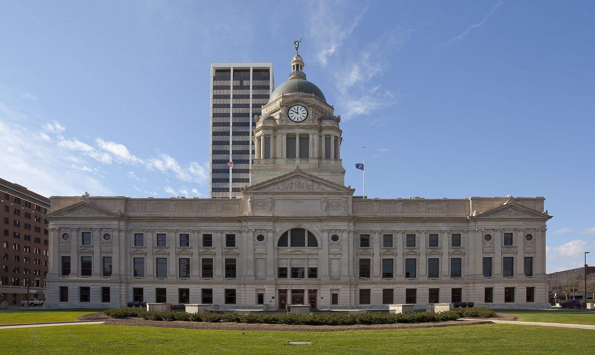 The domed Allen County Courthouse in downtown Fort Wayne under a blue sky, with an office tower behind it.