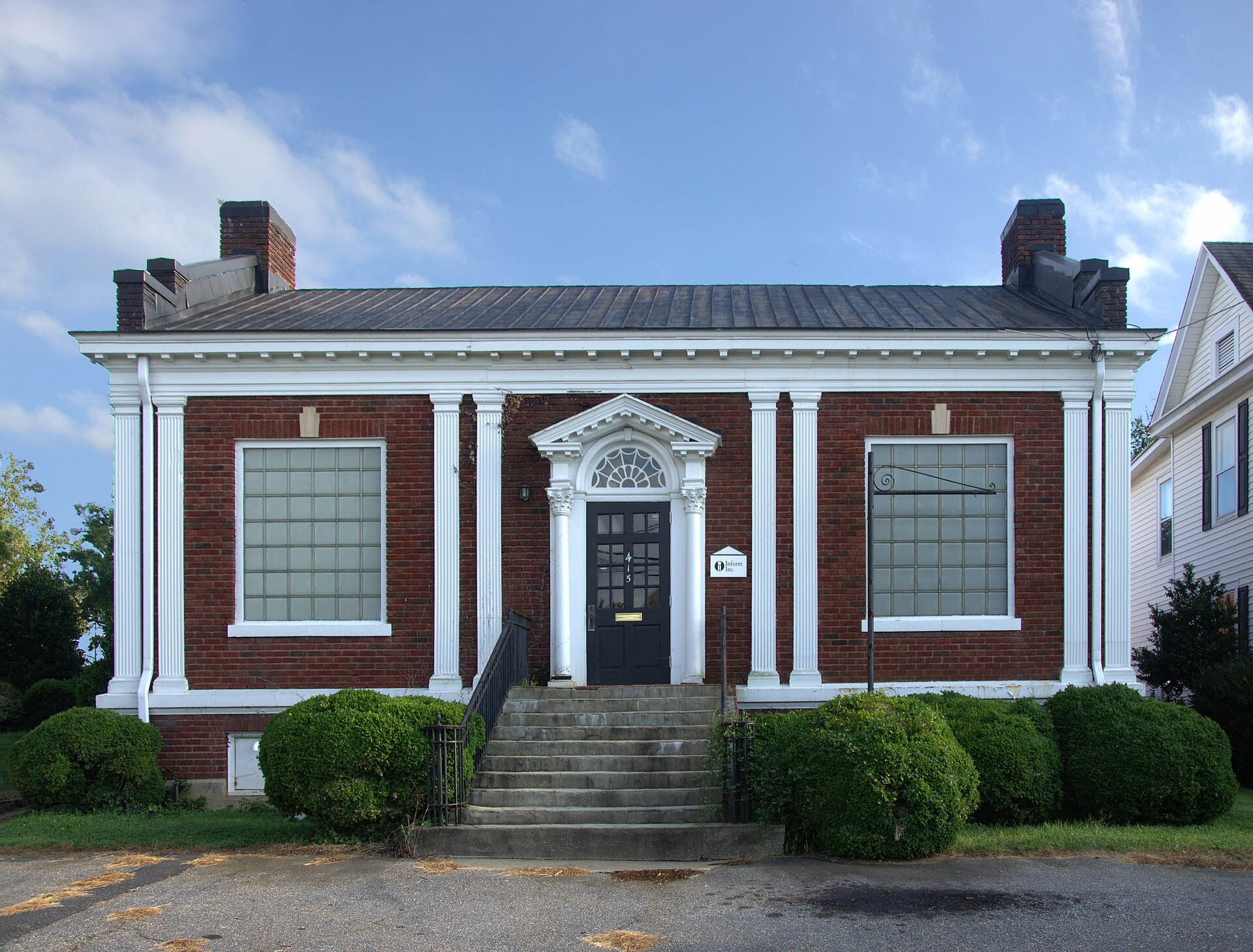 The red-brick Elliott Carnegie Library in Hickory, with its white columns and arched doorway, under a blue sky.