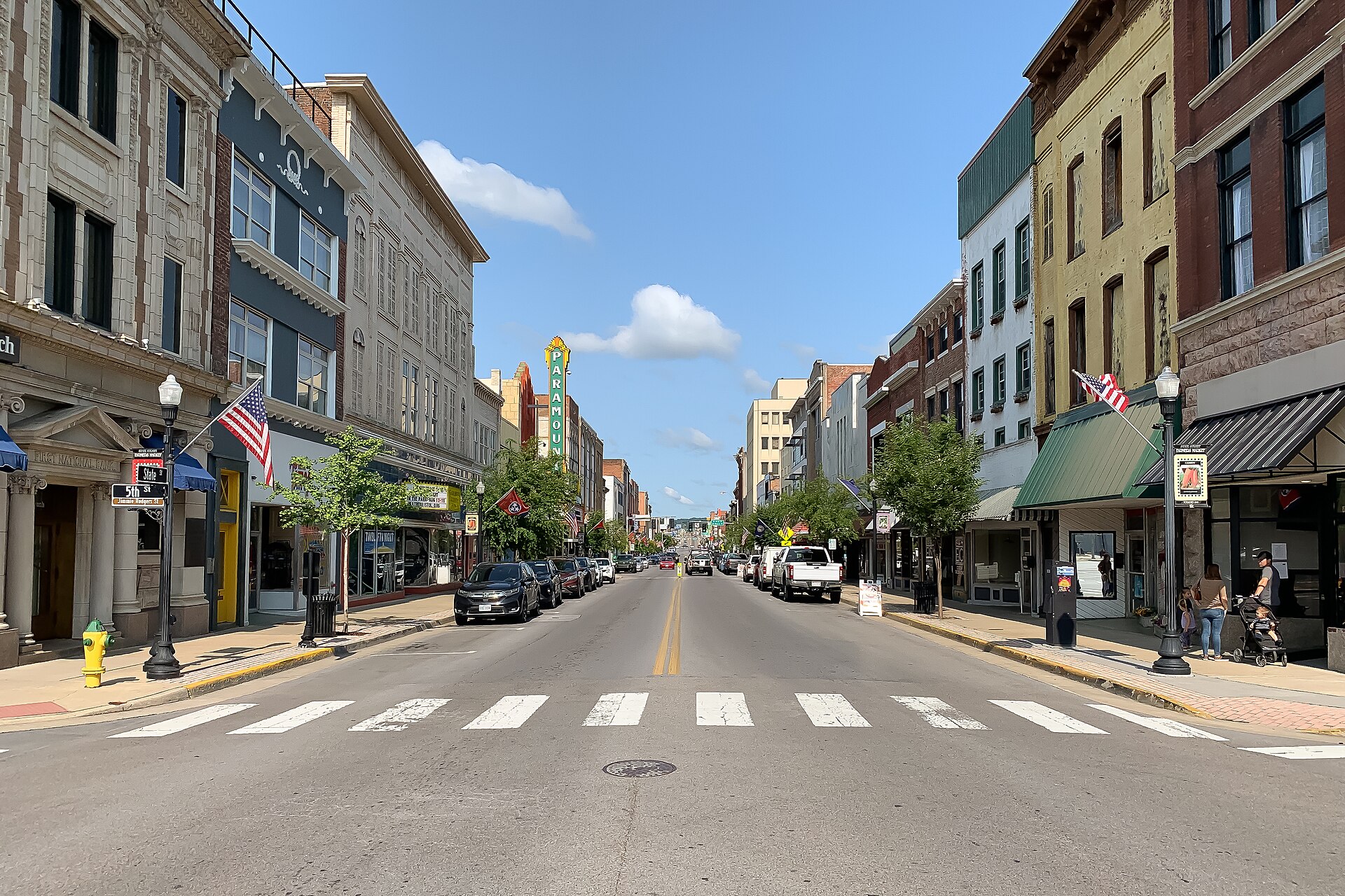 Historic storefronts and flags along sunny State Street in downtown Bristol, where the Tennessee–Virginia line runs down the street.