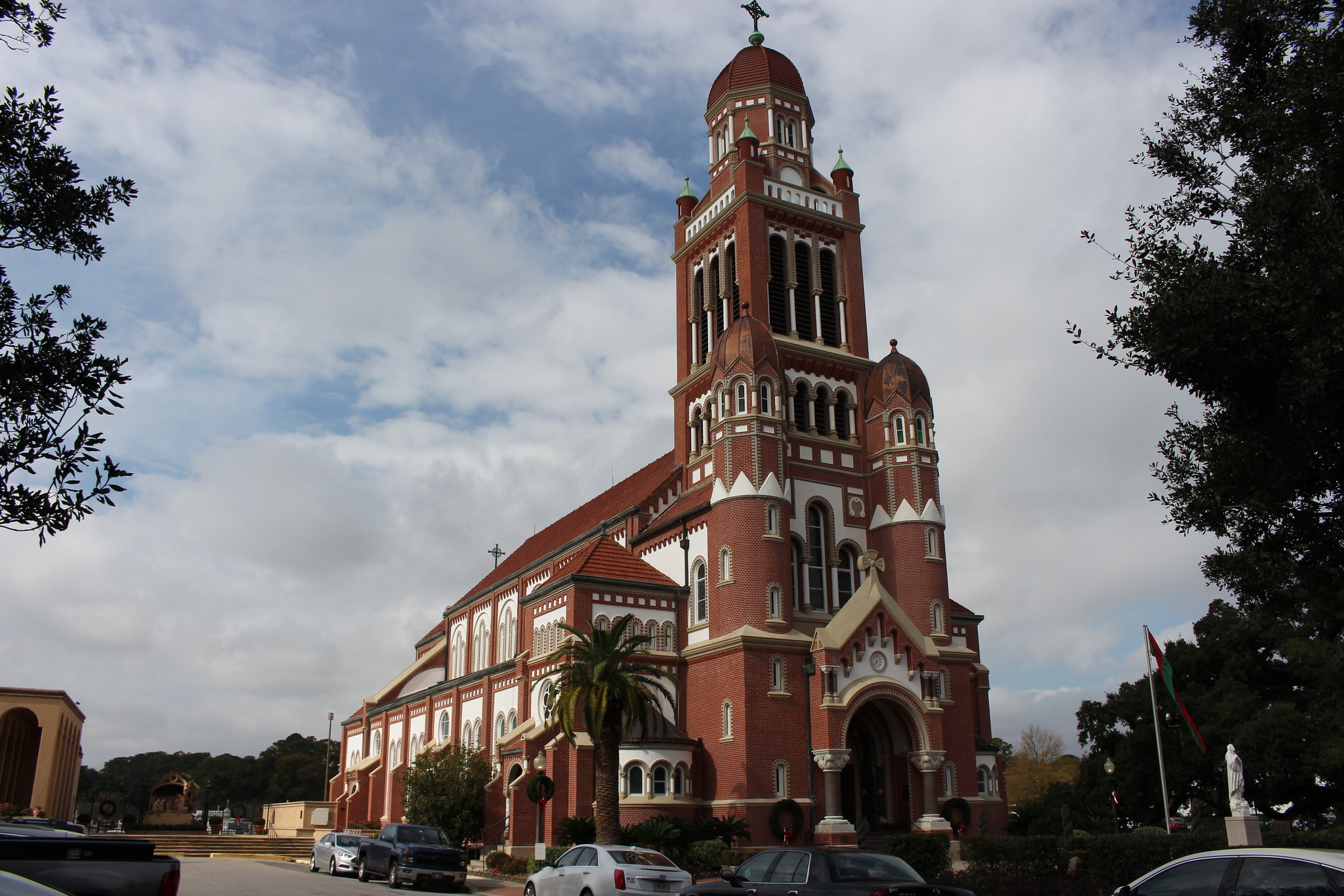 The red-brick Cathedral of St. John the Evangelist in Lafayette, its tall bell tower rising against a cloudy sky.