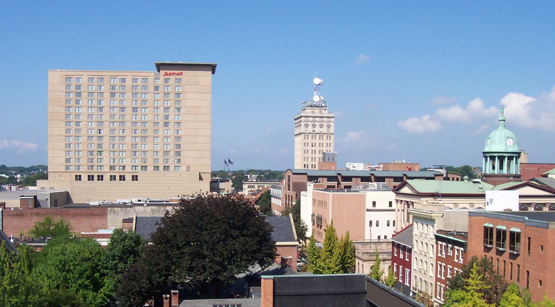 Downtown Lancaster's rooftops, the Griest Building tower and a green copper cupola under a blue summer sky.
