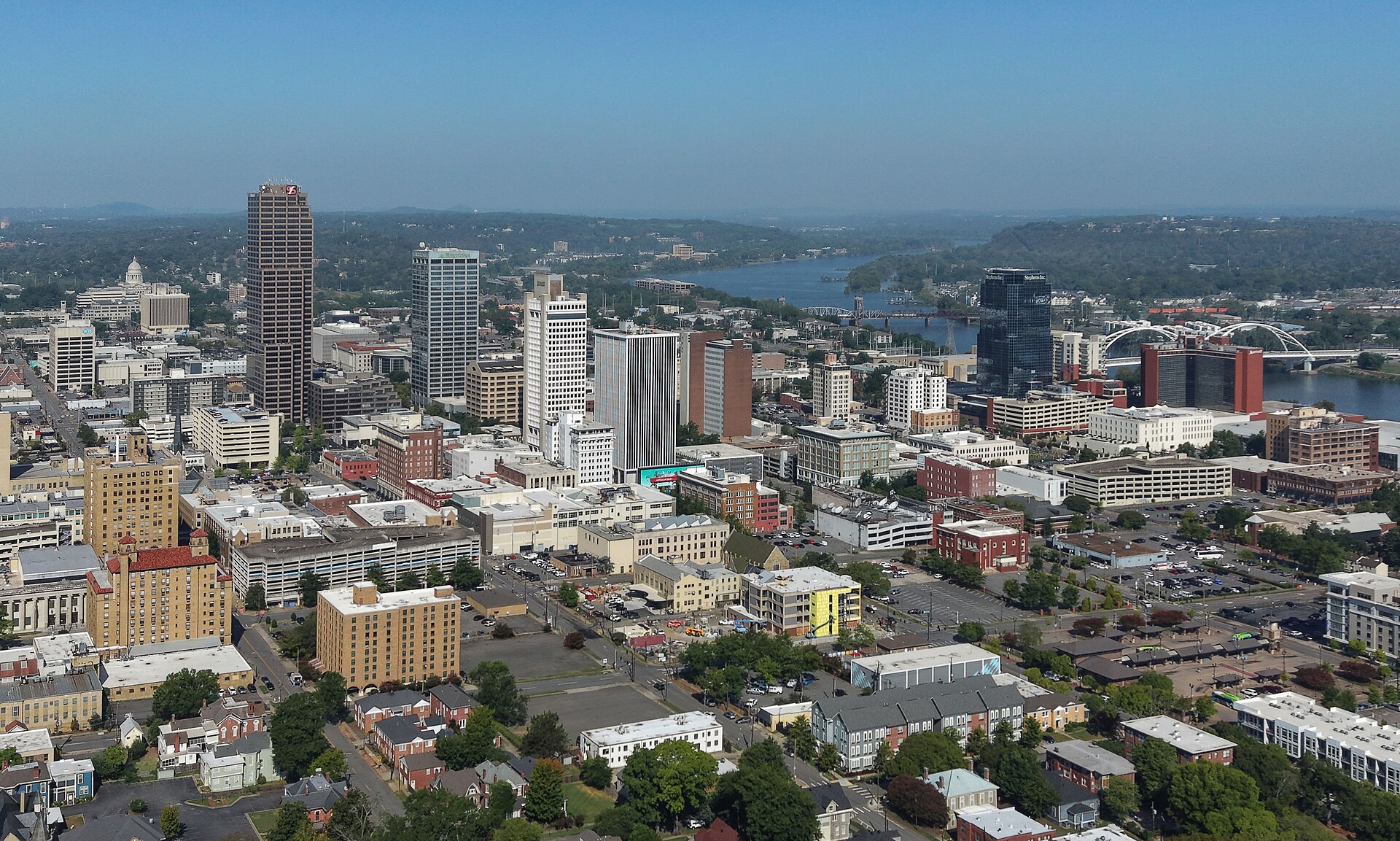 Downtown Little Rock towers with the Arkansas River and its bridges beyond, seen from above on a clear day.