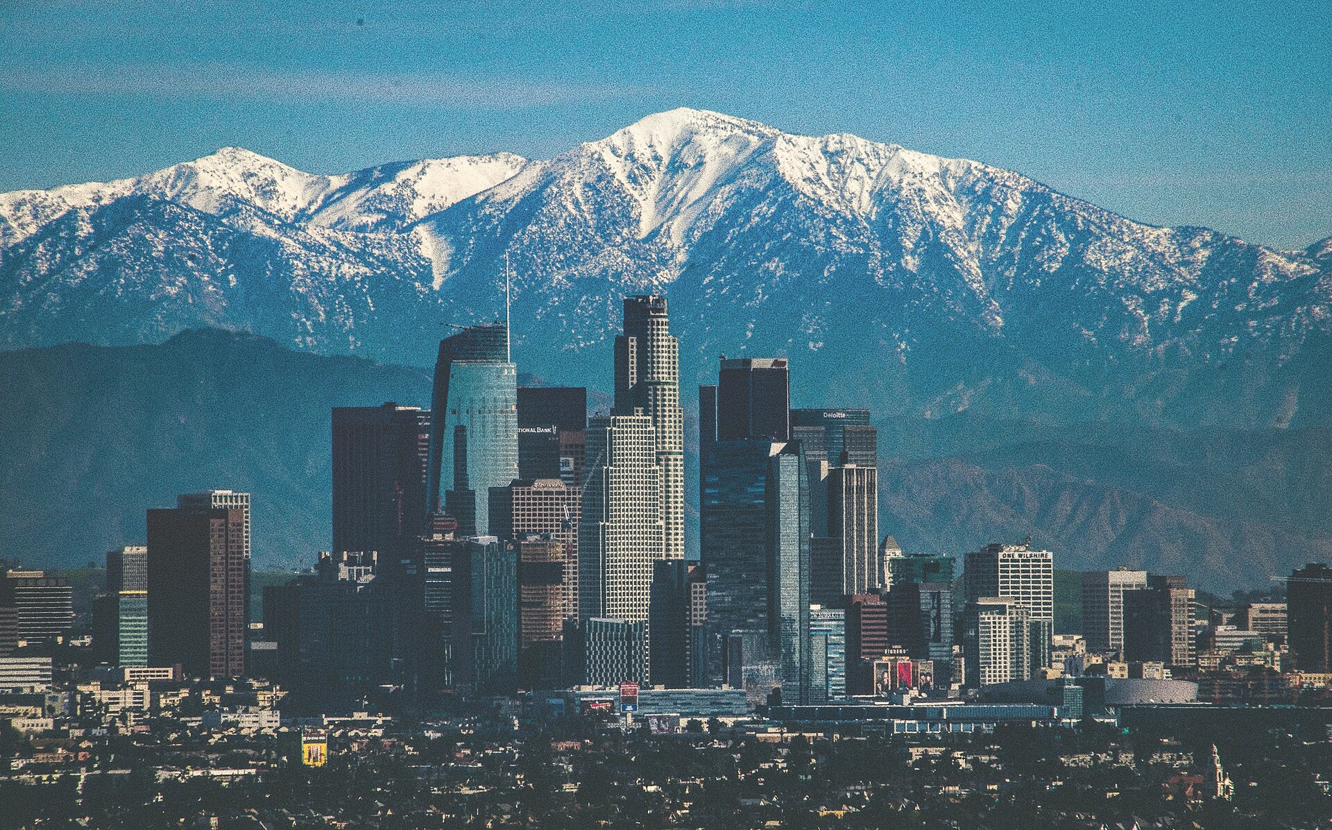 Downtown Los Angeles's towers in front of the snow-capped San Gabriel Mountains on a clear winter day.