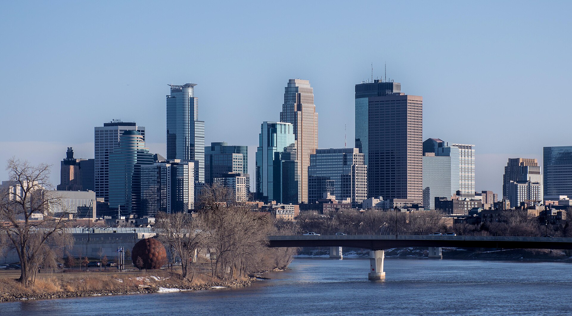 The Minneapolis skyline rising beyond the Mississippi River and a bridge on a clear winter day.