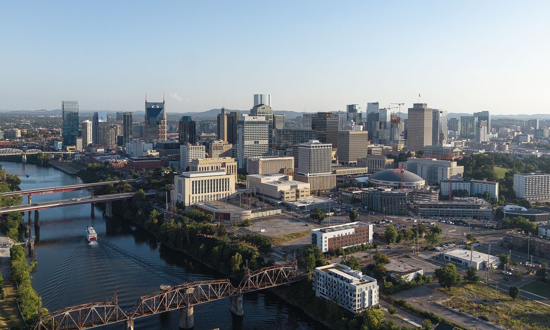 Downtown Nashville skyline above the Cumberland River and its bridges on a clear, sunny day.