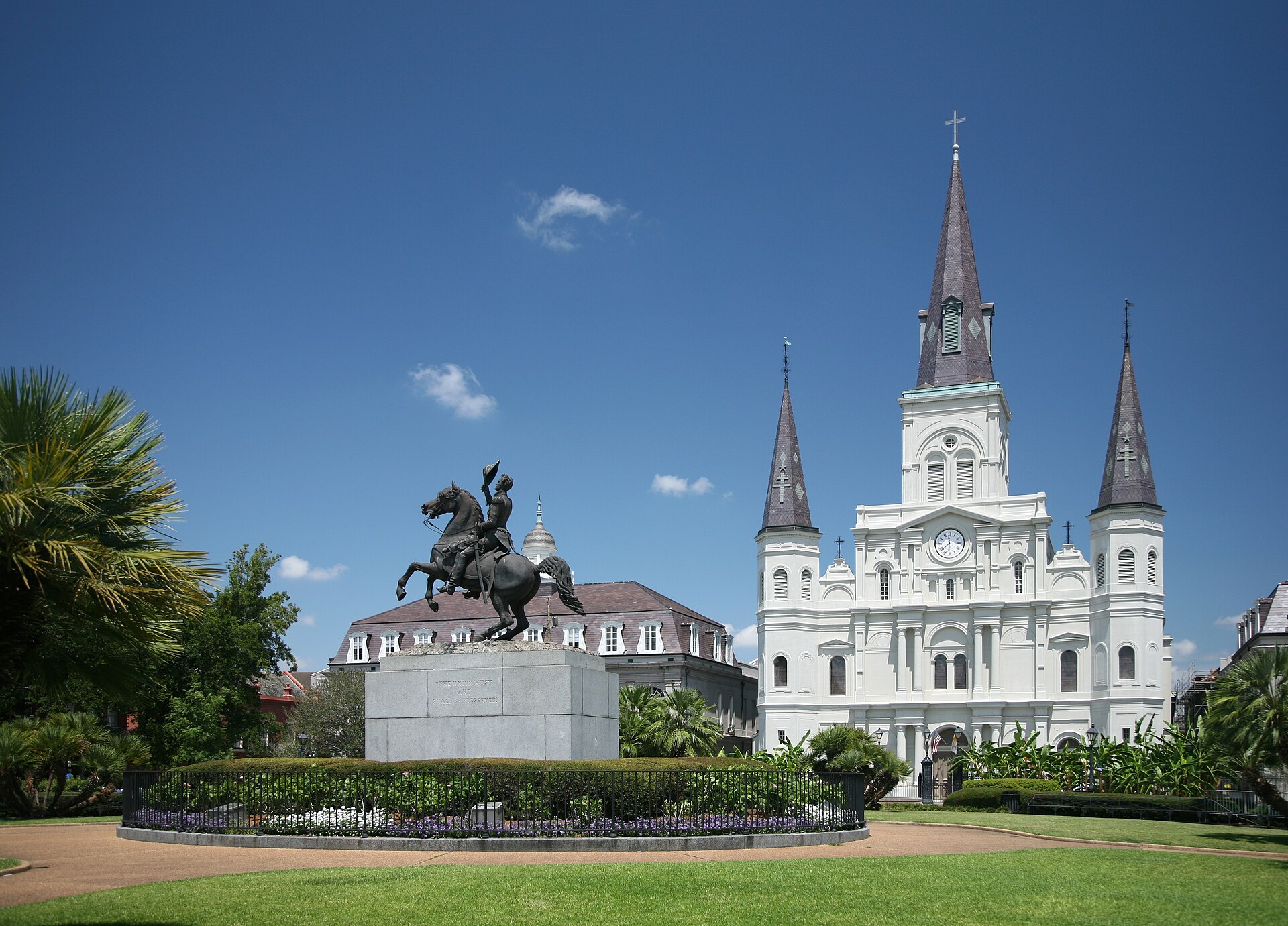 St. Louis Cathedral rising behind the Andrew Jackson statue in Jackson Square, New Orleans, under a deep blue sky.