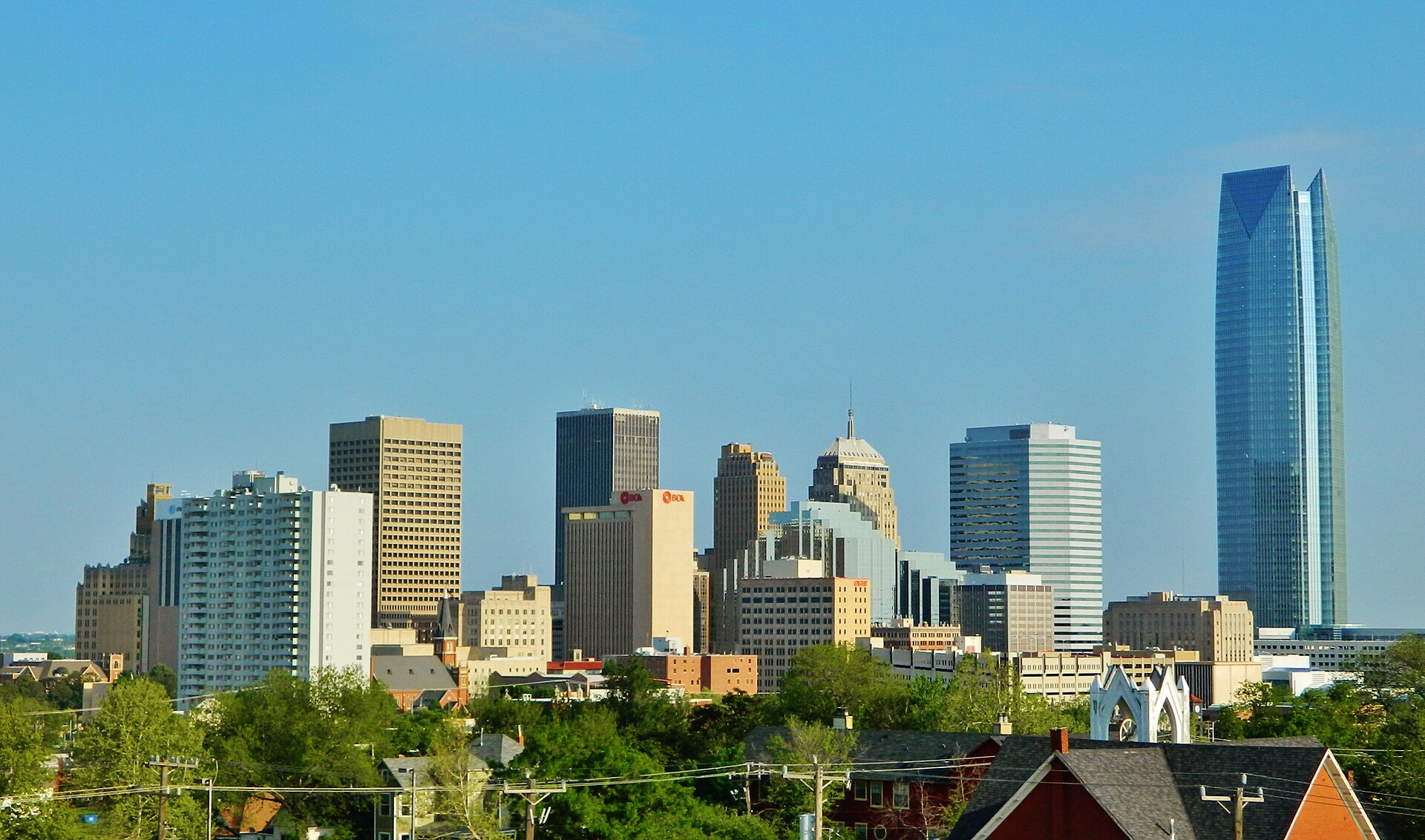 Downtown Oklahoma City skyline with the glass Devon Energy Center tower against a clear blue sky.