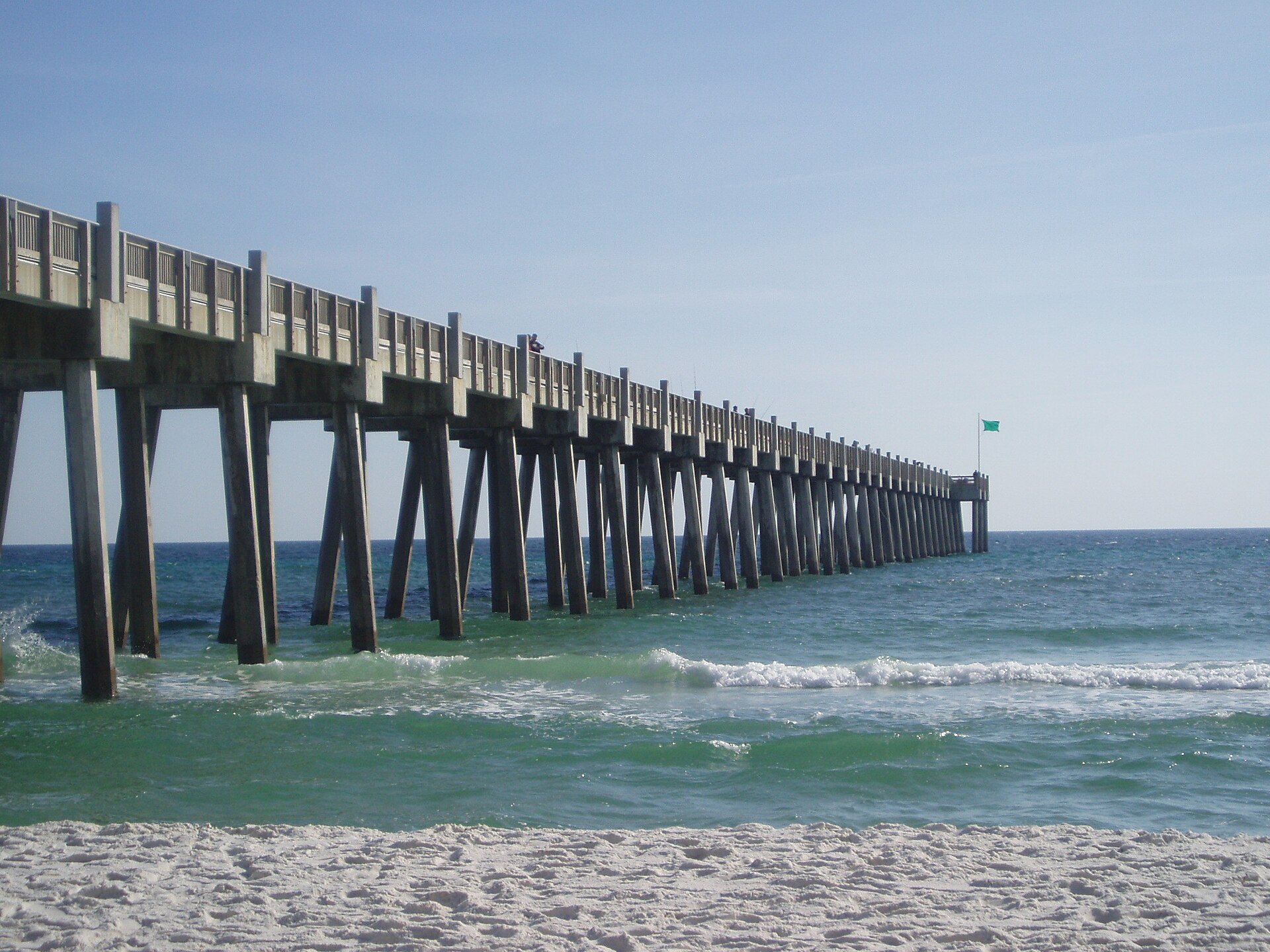 The long concrete Gulf Pier stretching over emerald-green surf from the white sand of Pensacola Beach.