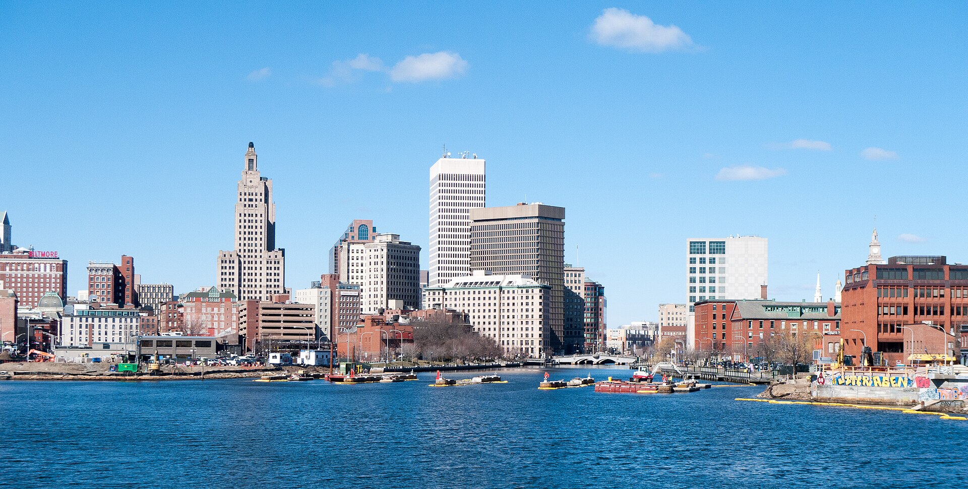 Downtown Providence's towers, led by the Art Deco Industrial Trust Building, across the Providence River on a sunny day.