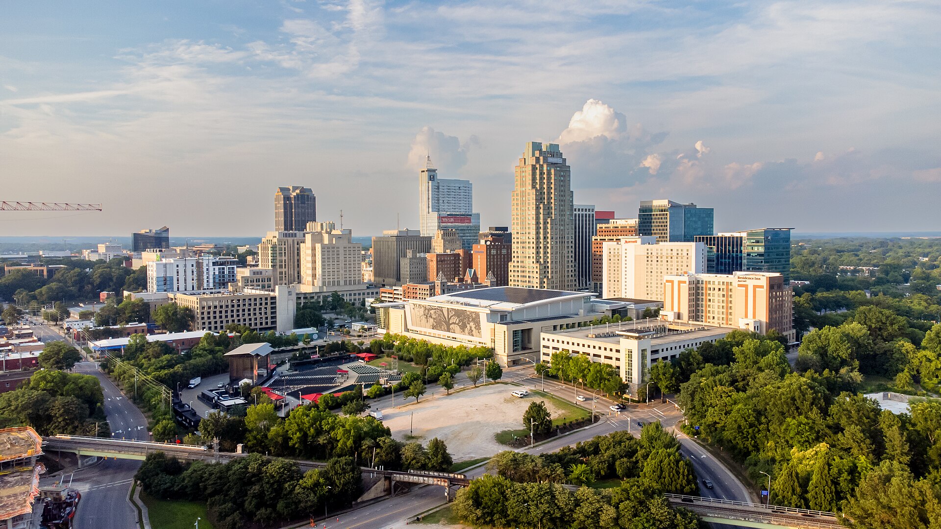 Downtown Raleigh's skyline rising above leafy streets in warm late-afternoon light.