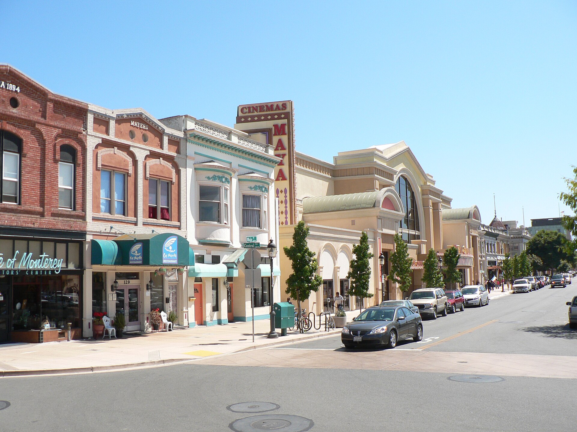 Historic brick and stucco storefronts and a cinema sign along sunny Main Street in Oldtown Salinas.
