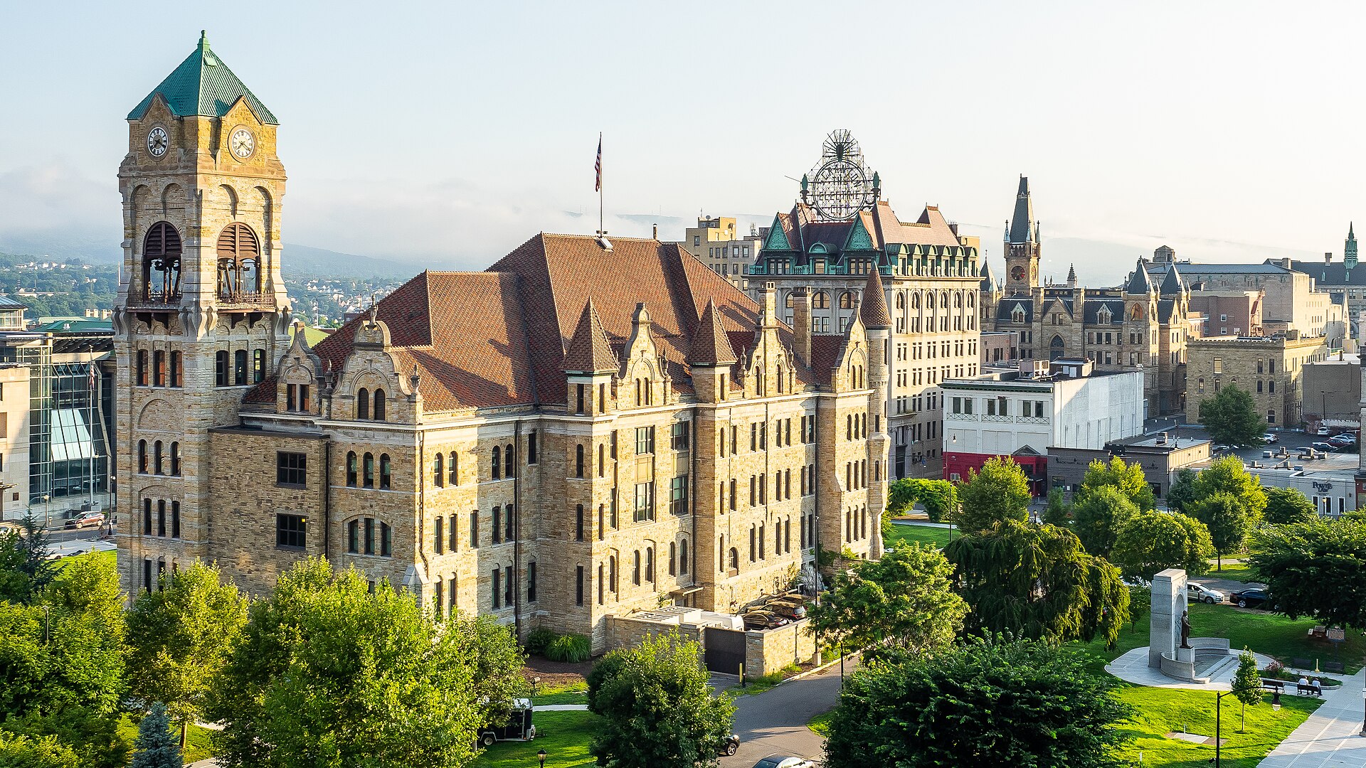 The clock tower of the Lackawanna County Courthouse and historic downtown Scranton buildings in warm sunlight.