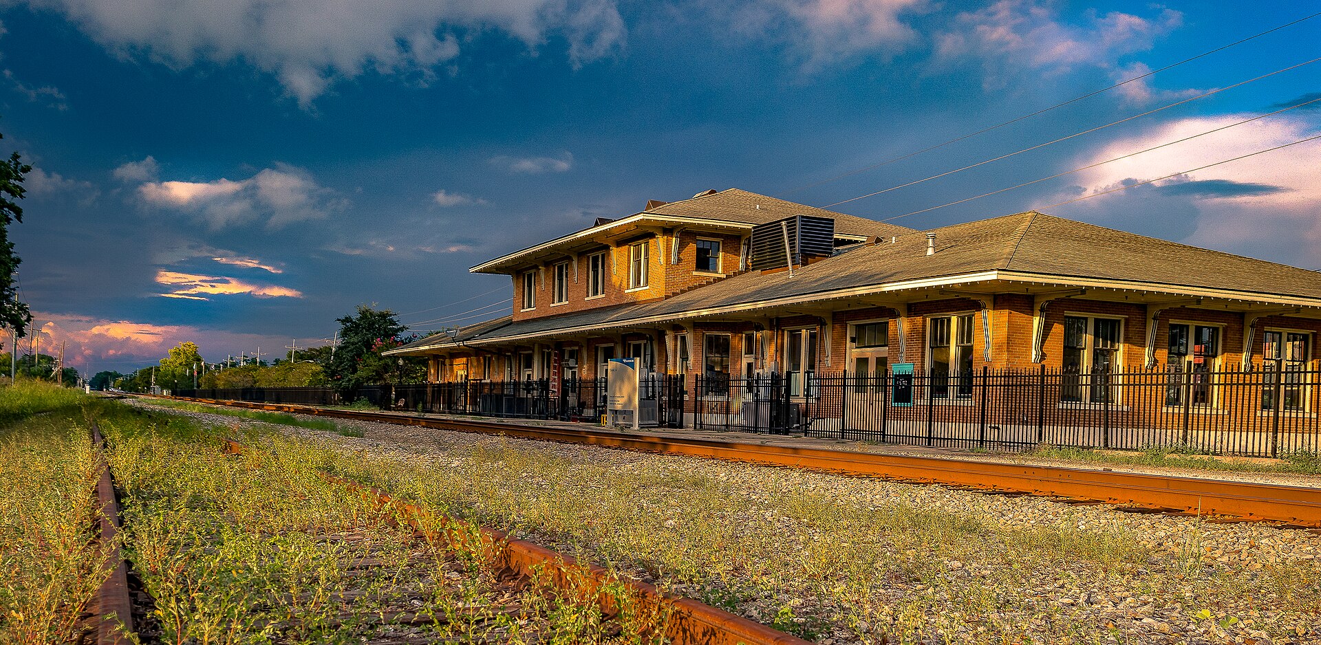 The historic brick railroad depot in Olde Towne Slidell beside the tracks in warm late-afternoon light.