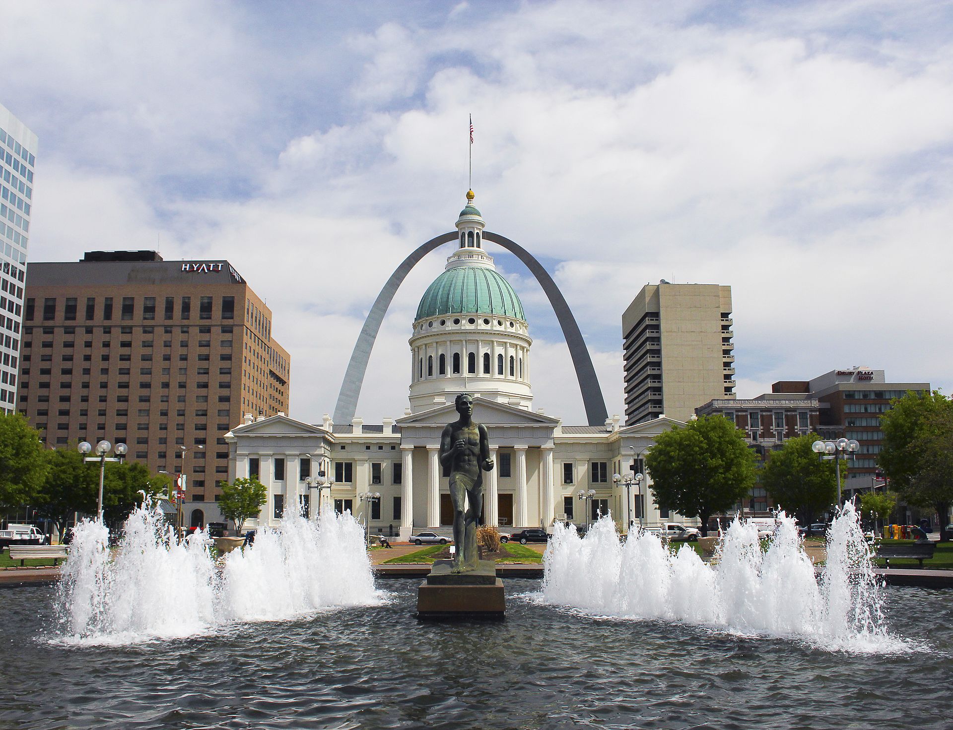 The Gateway Arch rising behind the green-domed Old Courthouse, seen across the fountains of Kiener Plaza in St. Louis.