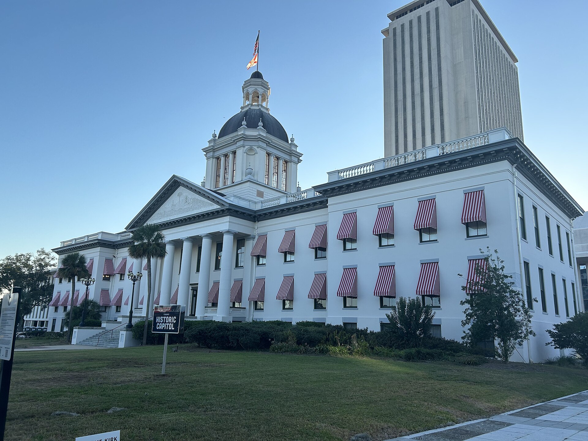 Florida's Old Capitol in Tallahassee, with red-and-white striped awnings, in front of the tall New Capitol tower.
