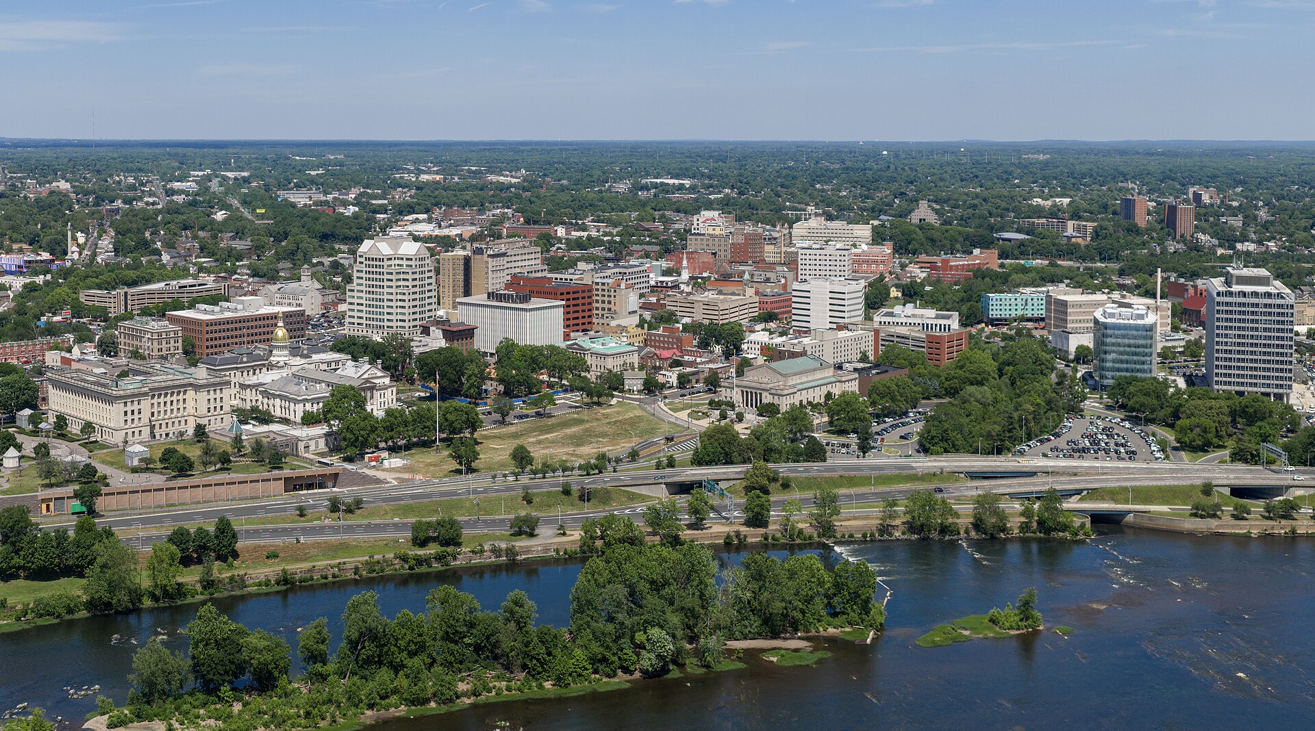 Downtown Trenton beside the Delaware River on a sunny summer day, with the gold-domed State House at left.